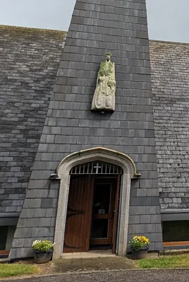 The stone door frame of St. Mary’s Church beneath a carved statue on the slate spire